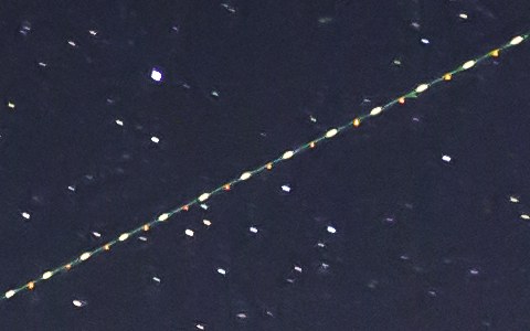 A plane trail: a diagonal row of white, red and green dots