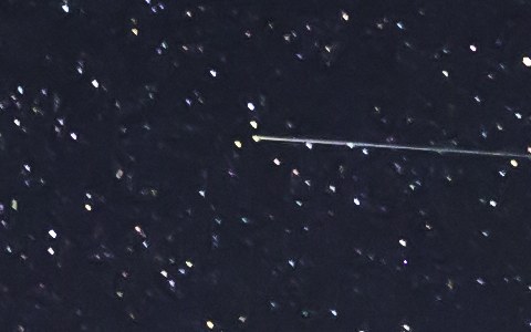A satellite trail: a thin line of even width that starts abruptly among the stars