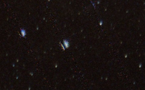 After, enlarged: the lines are gone, a faint dotted trace remains, one star has a dark slit through it, and one bright spot is gone